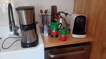 Keittiössä on kahvinkeitin, vedenkeitin, kahvipannu ja espressokone työtasolla.