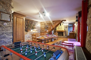 A cozy room with a foosball table, a dining area with a wooden table and chairs, and a staircase leading to another level. - Holiday Accommodation "Maison de pierre" with beautiful view (Saint-Gervais)