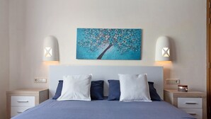 A bedroom with a bed, two bedside tables, a nightstand, a wall-mounted lamp, and a painting. - Villa "Montaña Roja" with Private Pool, Terraces, and Wi-Fi (Playa Blanca)