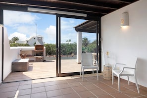 Un patio con dos sillas blancas, una mesita y un barril.