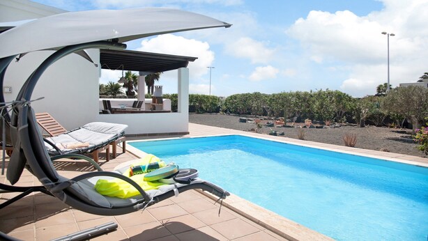 A swimming pool with lounge chairs and a covered seating area. - Villa "Montaña Roja" with Private Pool, Terraces, and Wi-Fi (Playa Blanca)