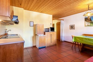 A compact kitchen with a sink, a microwave, and a refrigerator. There is a dining area with a table and chairs.