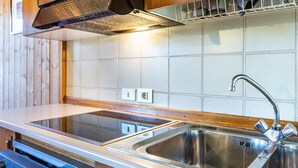 A kitchen with a stainless steel sink, wooden cabinets, a built-in oven, and a tiled backsplash.