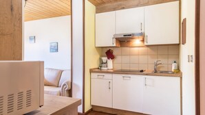 A compact kitchen with white cabinets, a wooden countertop, a built-in oven, and a coffee maker. - 'Pension Sonia Apartment 104' with Mountain View, Garden & Wi-Fi (Funes)