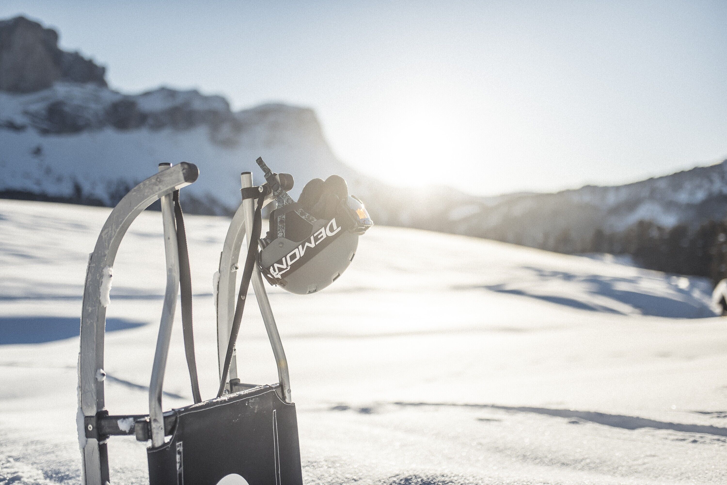 A snow-covered landscape with a metal structure, possibly a ski lift, and a helmet hanging from it.
