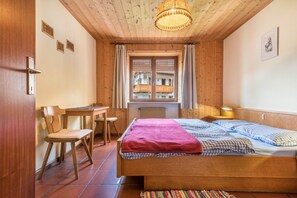 A wooden room with a bed, a desk, and a chair.