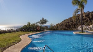 Una piscina de vora corba, un bou salvavides i una palmera.