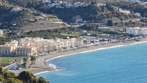 Un poble costaner amb edificis al costat de la platja, vista clara del mar i un fons d'altures.