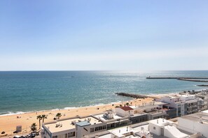 A coastal cityscape with a beach, buildings, and a clear sky.