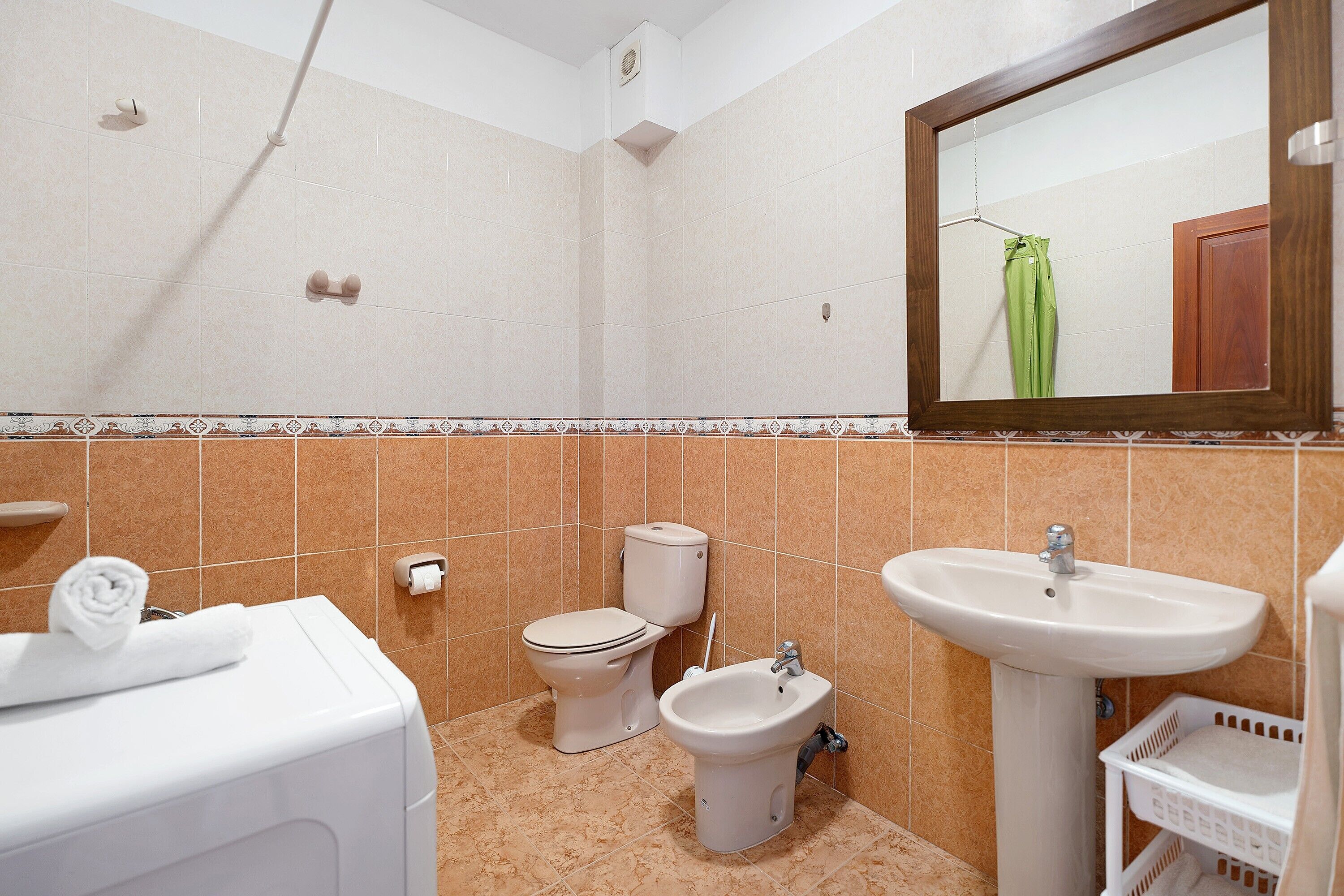 Un baño con inodoro, bidé, lavabo y toallero.