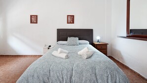 Habitación de hotel con cama, mesita de noche, lámpara y dos cuadros colgados en la pared.