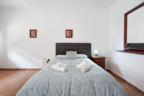 A hotel room with a bed, a nightstand, a lamp, and two wall-mounted picture frames.