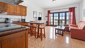 Una cocina con armarios de madera, encimera de granito y un comedor con sofá y mesa.