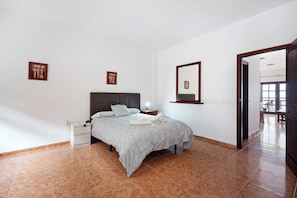 A bedroom with a bed, nightstand, and a door leading to another room. - Holiday Home Timarasan with Sea View, Terrace & Wi-Fi (El Pueblo)