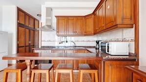 Una cocina con armarios de madera, encimera de granito, microondas blanco y campana extractora de acero inoxidable.