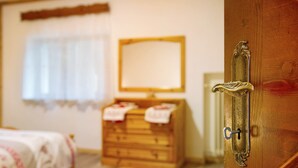 A bedroom with a wooden dresser, a bed with a floral bedspread, and a mirror on the wall. - Apartment 'Lorenzo' with Mountain View, Balcony and Wi-Fi (Vodo)