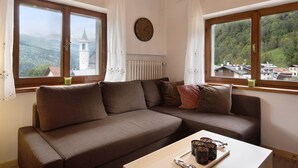 A room with a brown sofa, a wooden table with a tray, and two windows with curtains. - Apartment 'Lorenzo' with Mountain View, Balcony and Wi-Fi (Vodo)