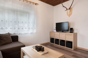 Un saló amb un sofà, una taula de centre amb tasses, un televisor sobre un moble de fusta i un crani de cérvol a la paret.