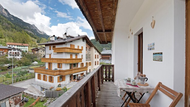 A balcony with wooden railings, a table with chairs, and a view of buildings and mountains in the background. - Apartment 'Lorenzo' with Mountain View, Balcony and Wi-Fi (Vodo)