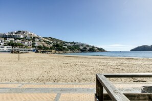 A beach with a wooden walkway leading to a building with multiple floors, situated on a hillside overlooking the sea. - Holiday Home "Casa en urb Cala Montgó" with Private Terrace and Wi-Fi (L'Escala)
