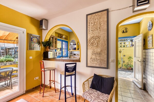 A kitchen with a blue door, a bar area with stools, and a dining table with chairs. - Holiday Home "Casa en urb Cala Montgó" with Private Terrace and Wi-Fi (L'Escala)