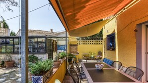 An outdoor patio with a table and chairs, surrounded by potted plants and a yellow wall. - Holiday Home "Casa en urb Cala Montgó" with Private Terrace and Wi-Fi (L'Escala)
