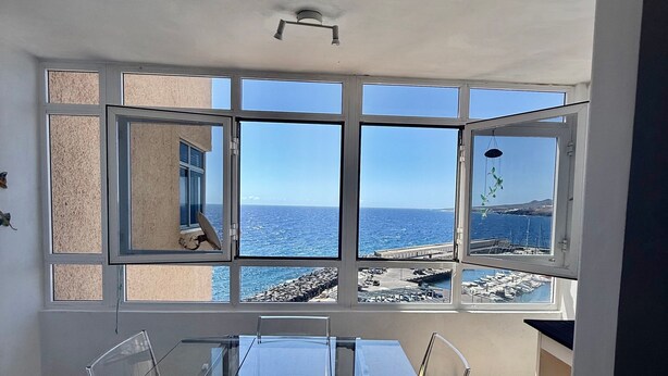 A room with a large window overlooking the sea, a glass table, and clear chairs. - Holiday Home 'Sea view Apartment' with Sea View, Shared Pool & Wi-Fi (Candelaria)