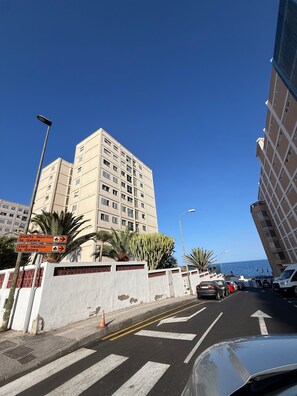 A street with a pedestrian crossing, a tall building, and a clear blue sky.