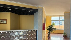 A spacious lobby with a marble floor, a reception desk with a decorative back panel, and potted plants. - Holiday Home 'Sea view Apartment' with Sea View, Shared Pool & Wi-Fi (Candelaria)