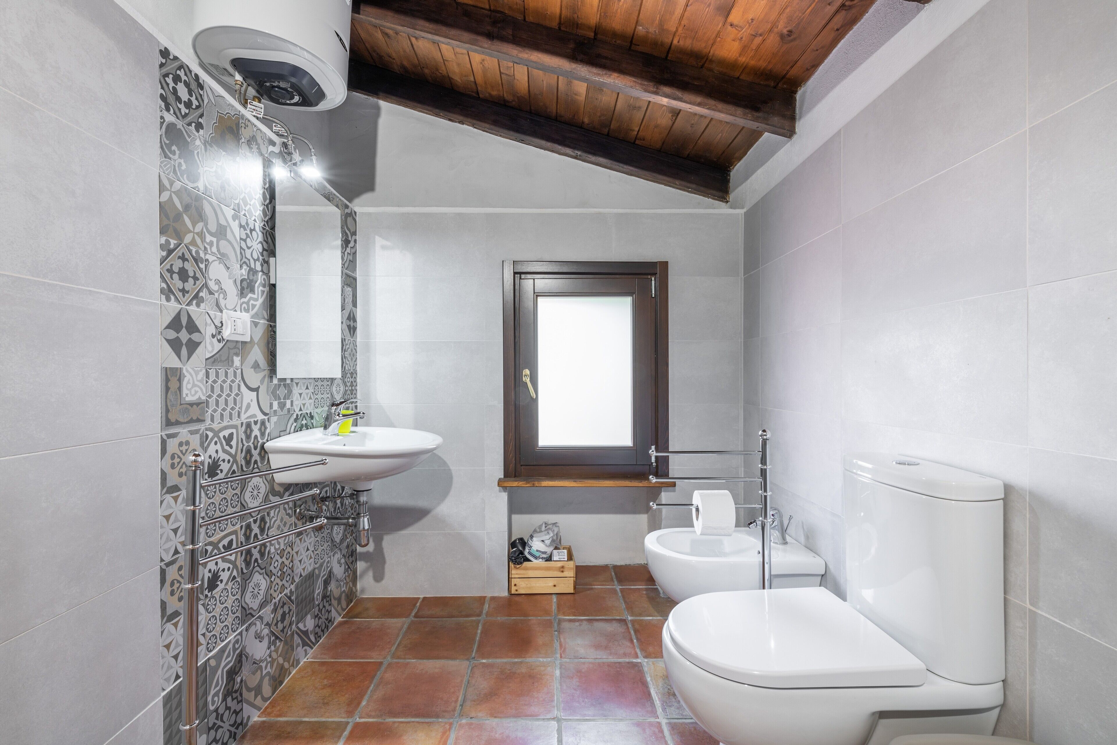 A bathroom with a sink, toilet, and window.