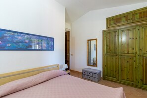A bedroom with a bed, a dresser, a mirror, and a painting on the wall.