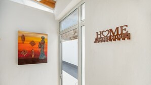 Eine Wand mit einem 'HOME SWEET HOME' Schild und einem Gemälde einer Person mit einem Vogel.