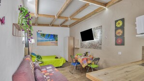 Ein Zimmer mit einem Bett, einem Tisch mit Stühlen, einem Fernseher und einem Bild an der Wand.
