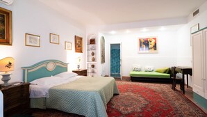 Een slaapkamer met een bed, een nachtkastje, een dressoir, een groene bank en een rood tapijt met een patroon.