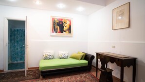 Een kamer met een bed, een bureau, een kamerbreed tapijt met een patroon en twee schilderijen aan de muur.