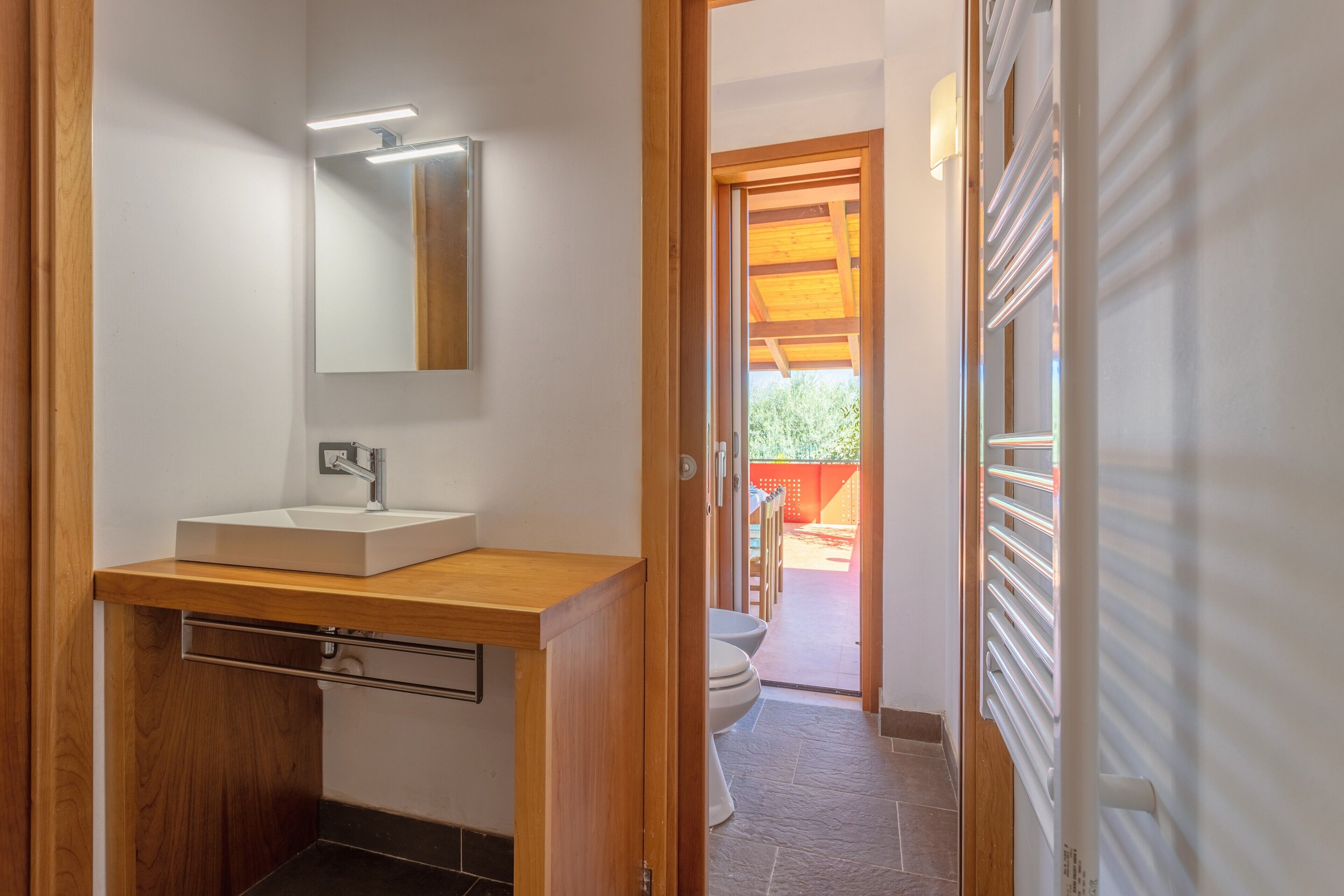 A modern bathroom with a wooden vanity, a mirror, and a toilet.