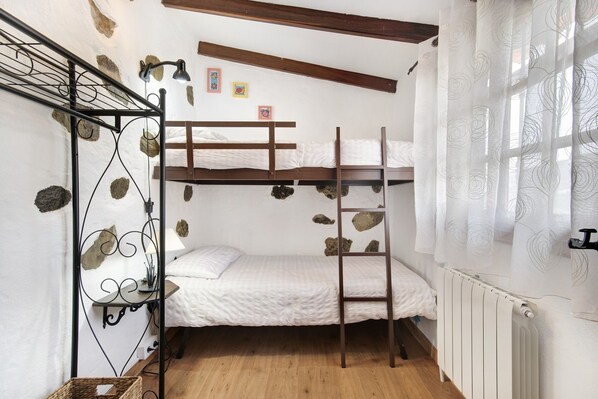 A bunk bed room with a ladder, a radiator, and a window with curtains.