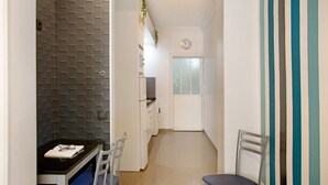 A kitchen with a black countertop, white cabinets, and a window. There is a dining area with a table and chairs.