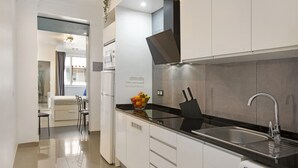 A modern kitchen with white cabinets, a stainless steel sink, and a built-in dishwasher.
