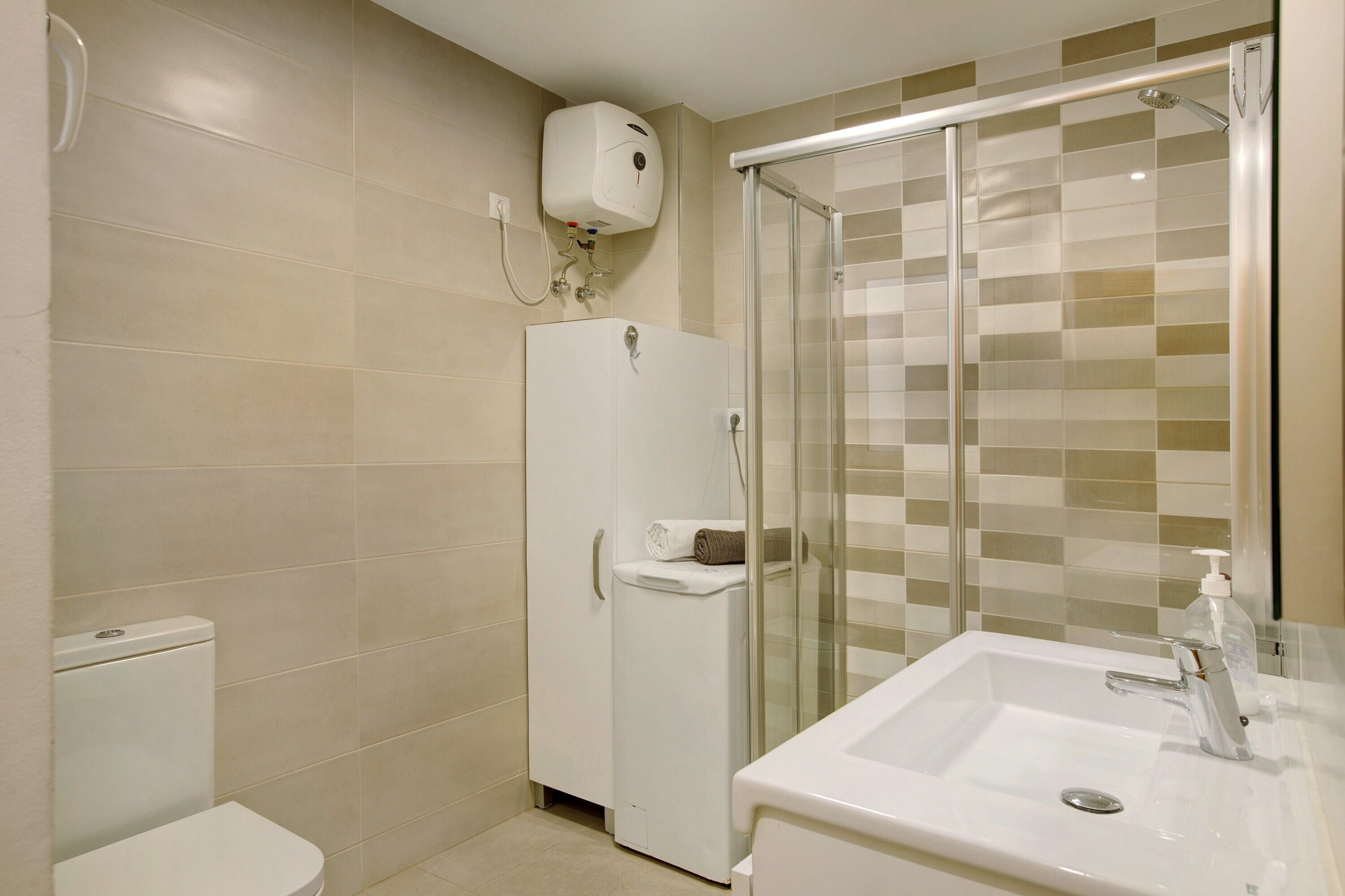 A bathroom with a toilet, a shower enclosure, and a sink.