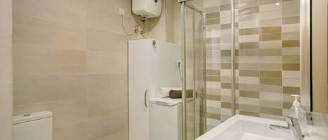 A bathroom with a toilet, a shower enclosure, and a sink.