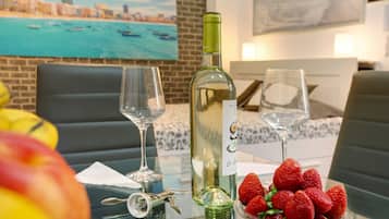 Une table à manger avec une bouteille de vin blanc, deux verres, un bol de fraises et une clé.
