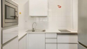A kitchen with white cabinets, a stainless steel sink, and a microwave.
