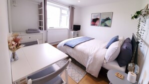 A bedroom with a bed, bedside table, TV, and a window with curtains. - Saltdean annexe, excellent location (Saltdean)