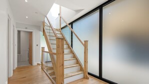 Un escalier en bois avec une rampe en verre menant à un deuxième étage.