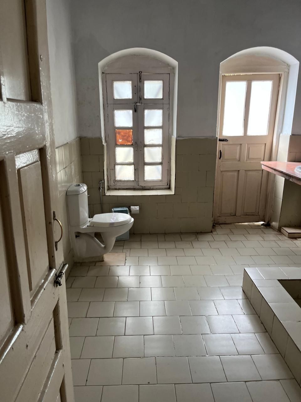 A bathroom with a toilet, bidet, and a window.