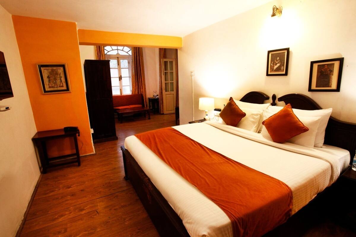 Habitación de hotel con una cama grande, una mesita de noche y una ventana con cortinas.