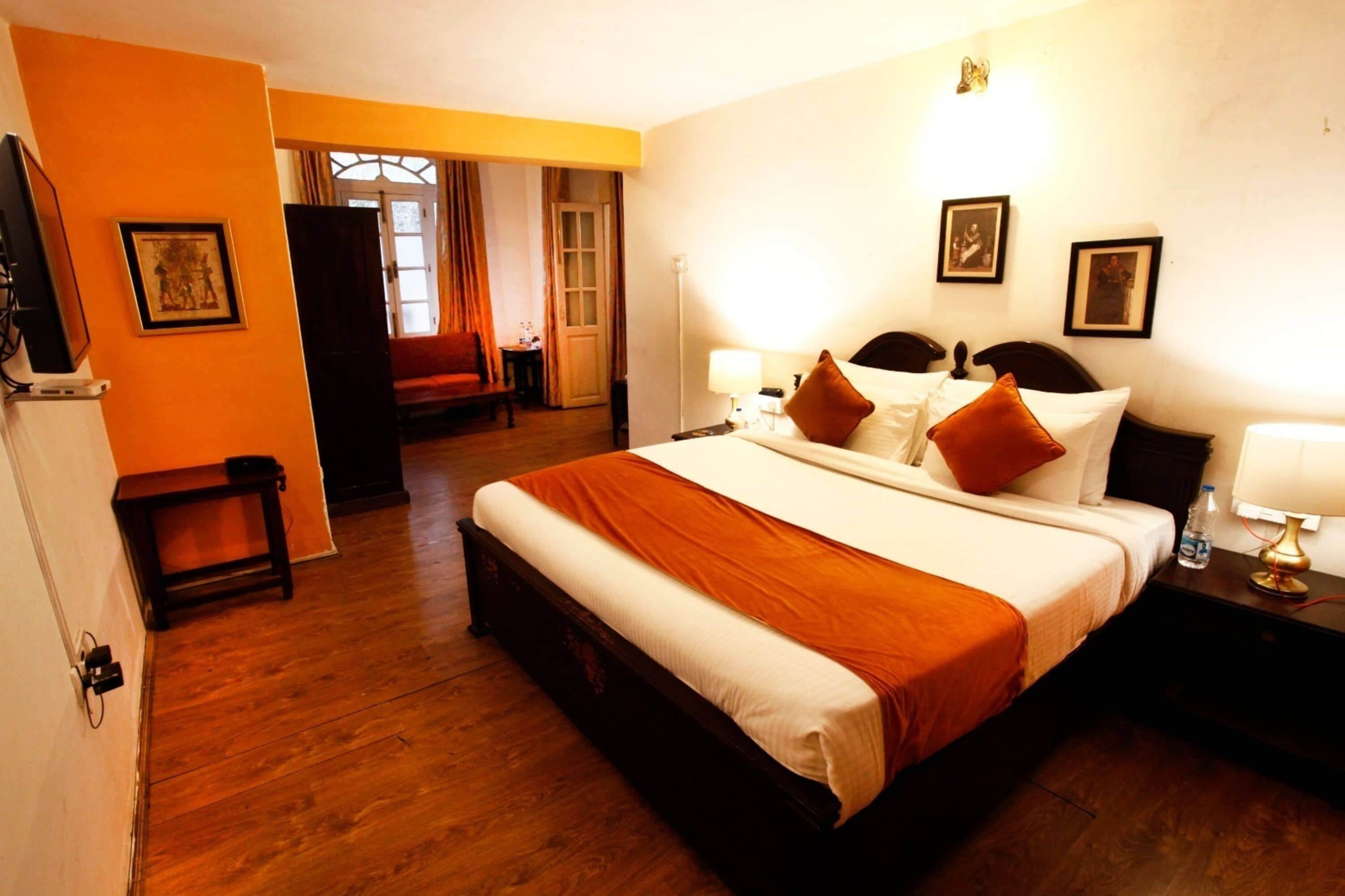 A hotel room with a large bed, a bedside table, a chair, and a door leading to a balcony.