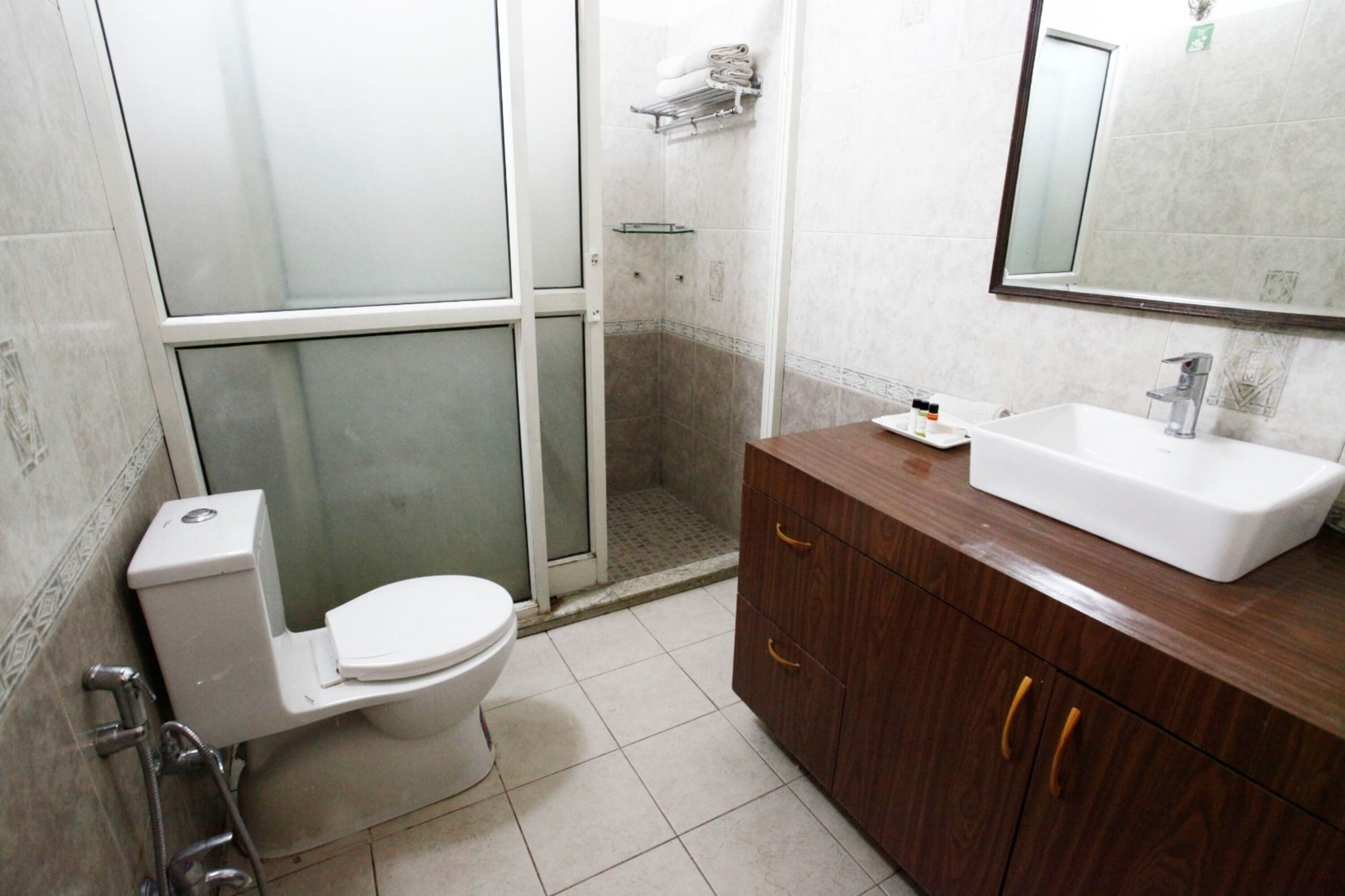 A bathroom with a toilet, shower, and vanity with a sink and mirror.