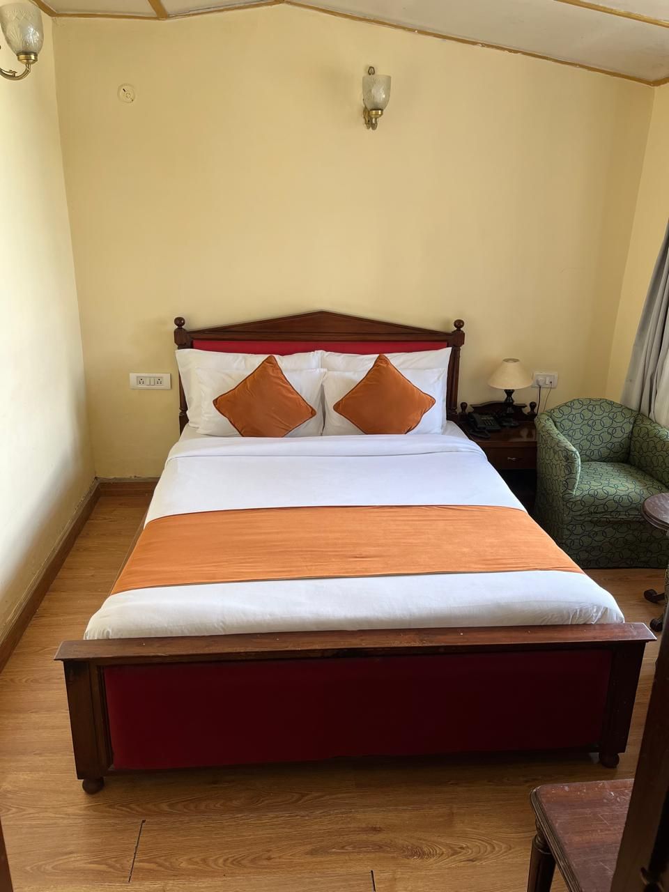 Una cama bien hecha con cabecera de madera, dos almohadas marrones y una colcha blanca.